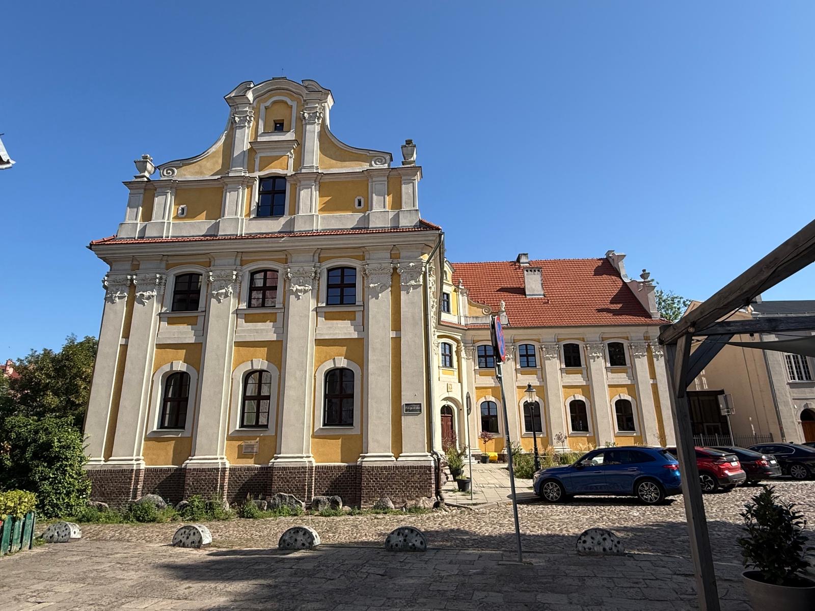 Barokowy kościół o żółtej fasadzie i przylegające zabudowania